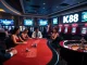 K88 casino players engaging at a high-stakes gaming table with vibrant slot machines in view.